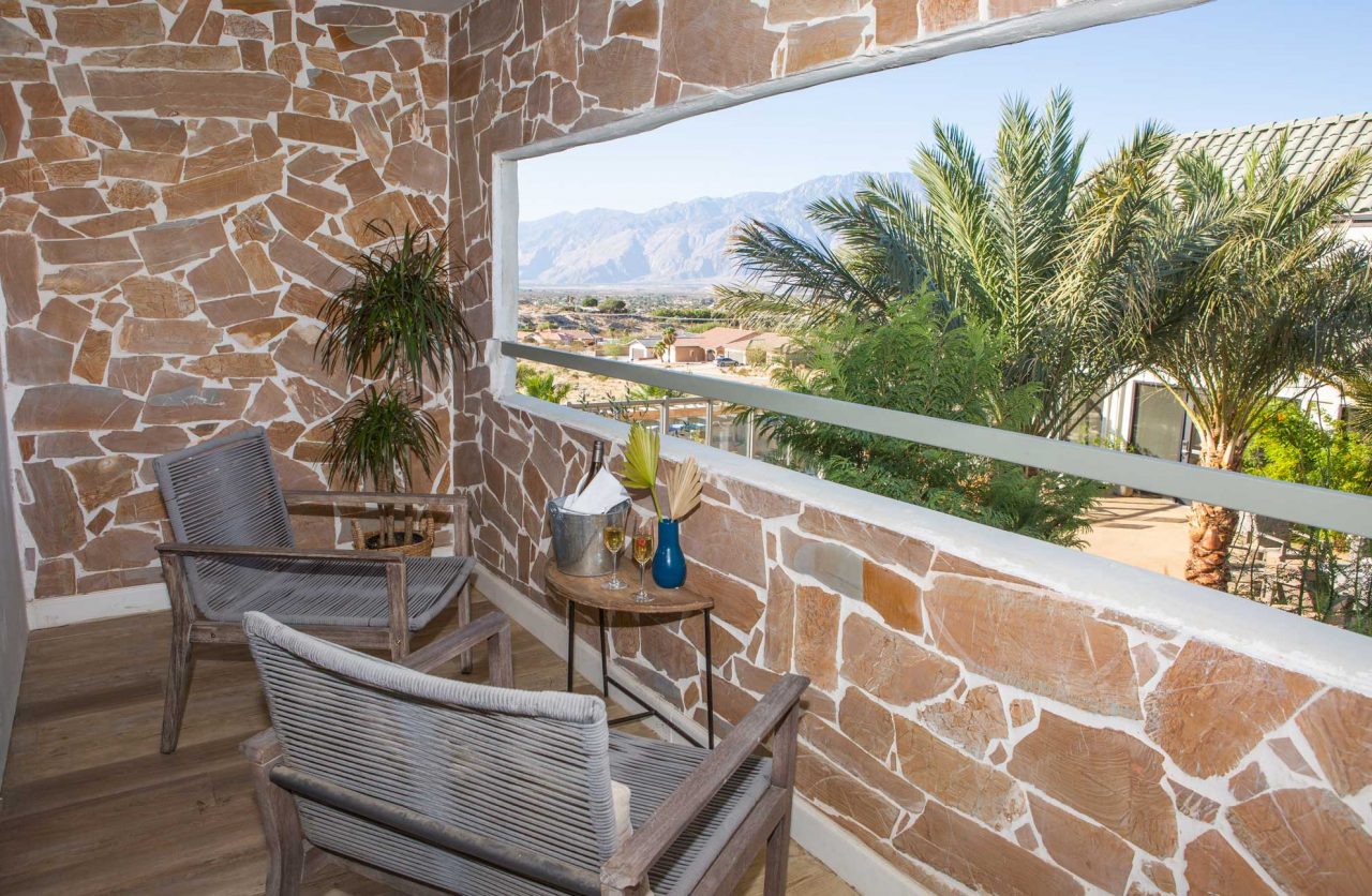 Hideaway King Room Balcony with Courtyard and Mountain View, 2 chairs and table with wine