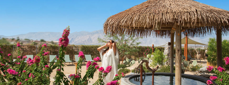 Woman standing near oasis tub with mountains in background